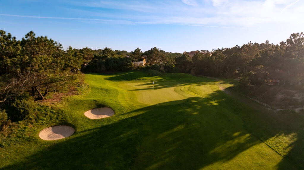 Fairway with bunkers and green with white flag at Praia d'el Rey Golf Course