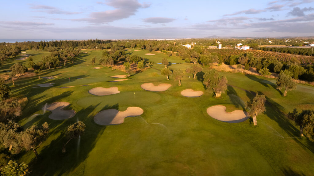 A green with bunkers around it and sprinklers on at Quinta De Cima Golf Course