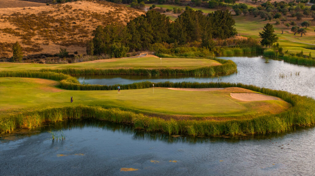 Person playing golf at Quinta do Vale Golf Course with lake around