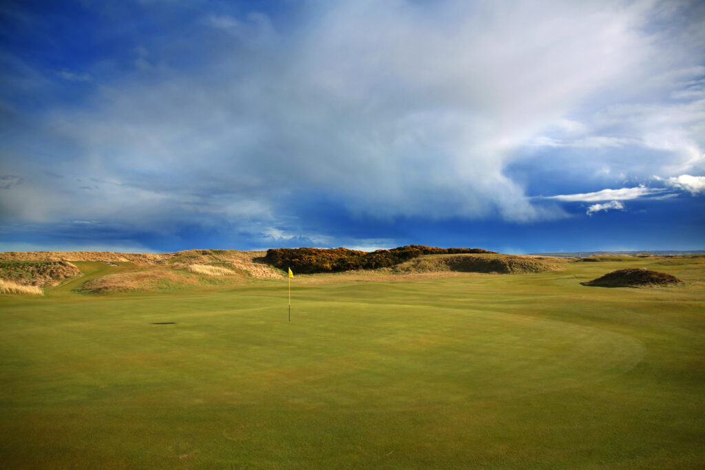 Hole with yellow flag at Balgownie Links at Royal Aberdeen Golf Club with mounds around