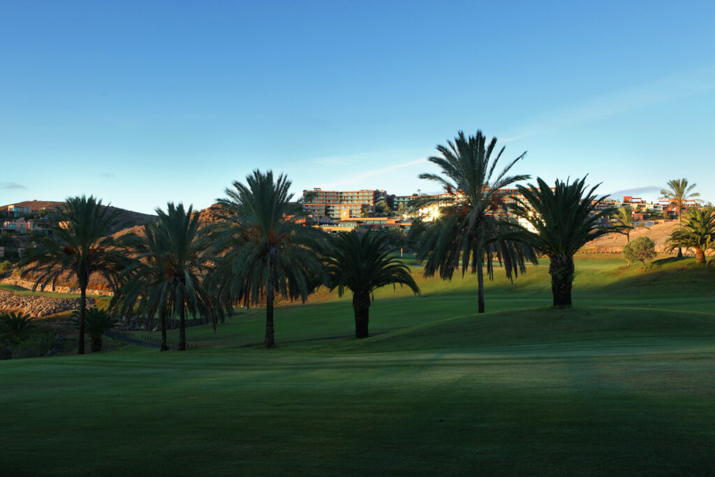 Fairway with trees around at Salobre Golf - Old Course with buildings in background