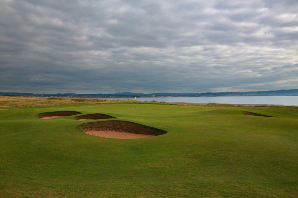 Hole with bunkers at The Castle Course at St Andrews with ocean in background