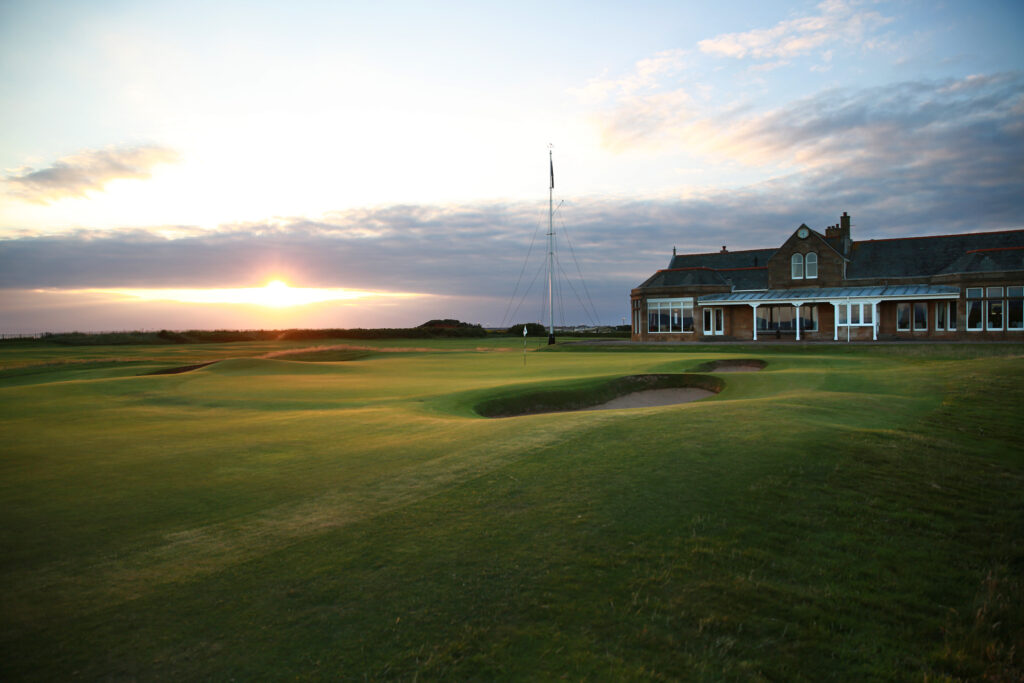 Hole with white flag and bunkers at The Castle Course at St Andrews with building in background