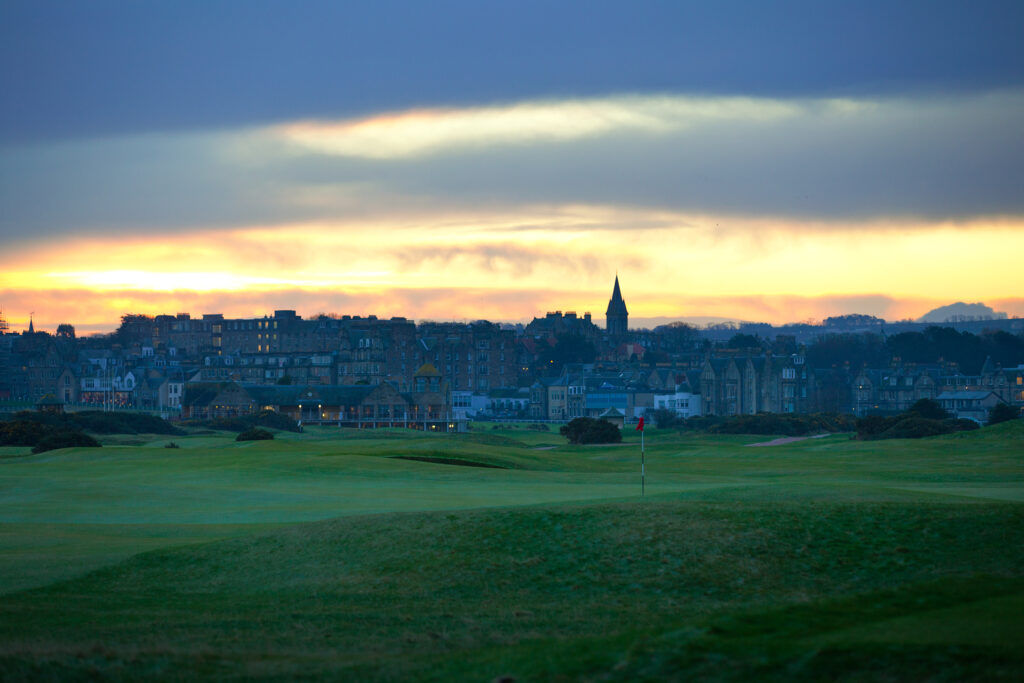 Hole with red flag at The Old Course at St Andrews with town in background