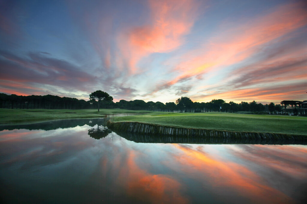 Fairway with lake and trees in background at Sueno Golf Club - Dunes Course at sunset