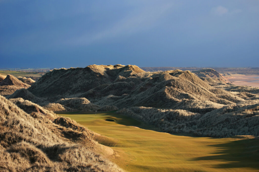 Fairway leading to hole with bunker at Trump International Golf Links with hills around