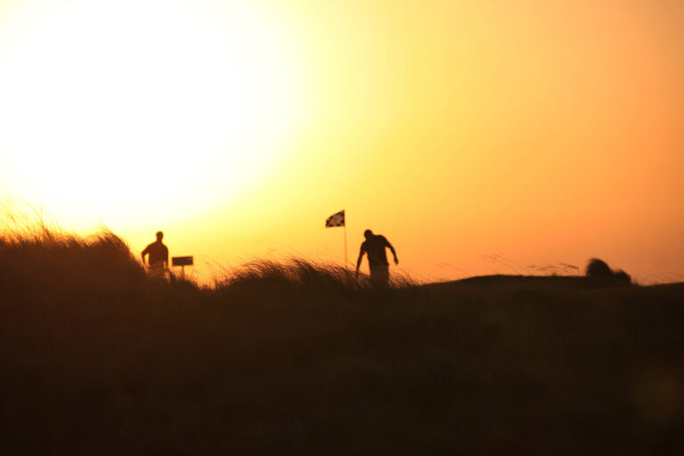 People playing golf at Yas Links Golf Club at sunset