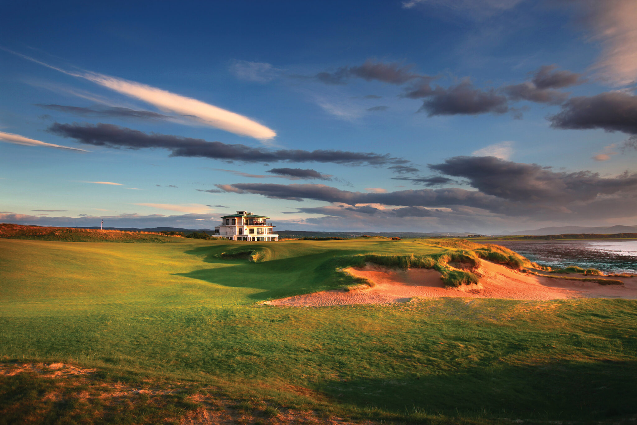 Bunker on fairway at Castle Stuart Golf Links with building in background and ocean view