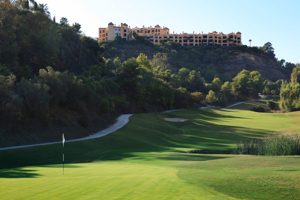 Hole with white flag with fairway in background with building on hilltop at La Quinta Golf Course