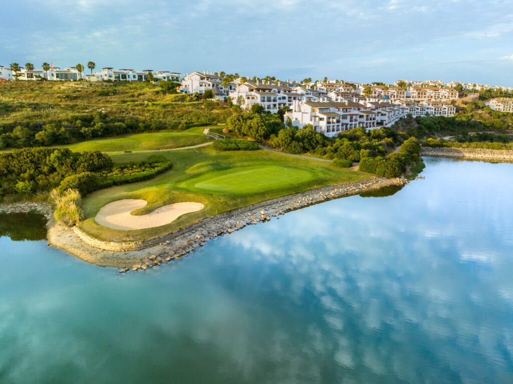 Lake with fairway and bunker and buildings in background at La Hacienda Alcaidesa Links Golf Resort - Heathland Course