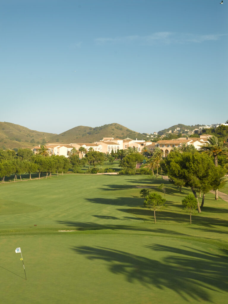 Fairway at La Manga Club North with trees around and buildings in background