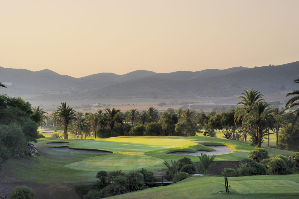 Hole with bunkers around at La Manga Club North with trees around and hills in distance