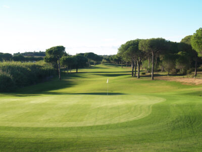 Hole with white flag and trees around at La Monacilla Golf Course