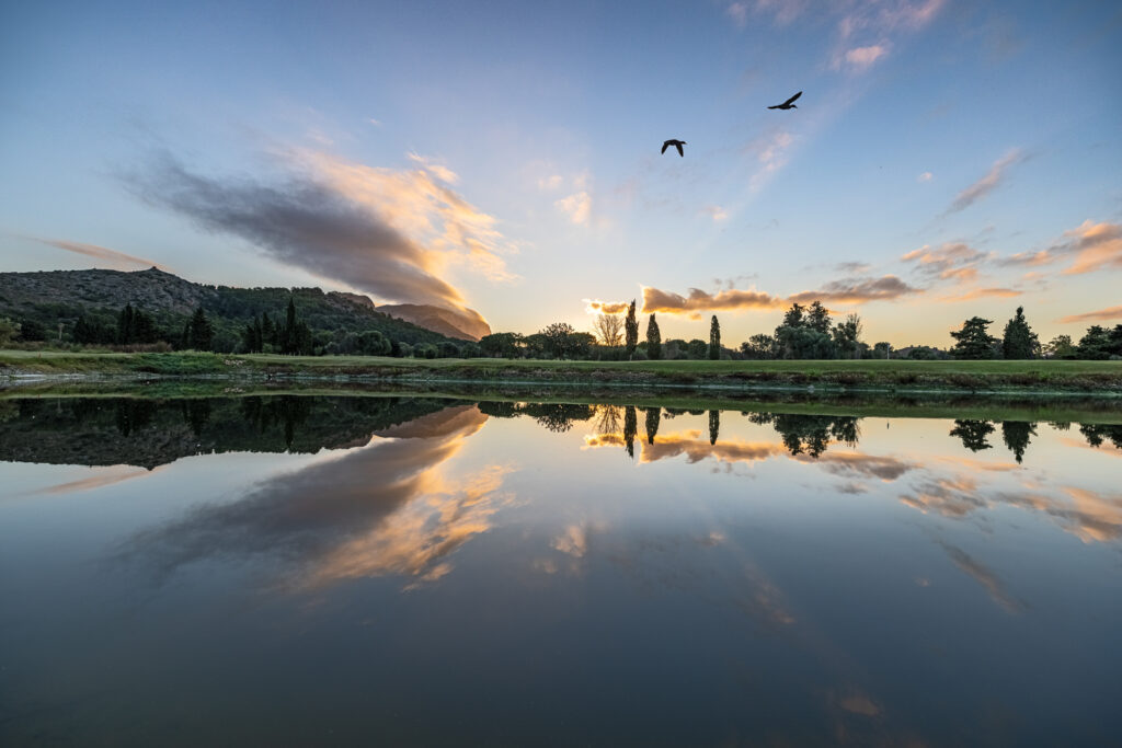 Lake with fairway in background and birds flying above at La Sella Golf Course