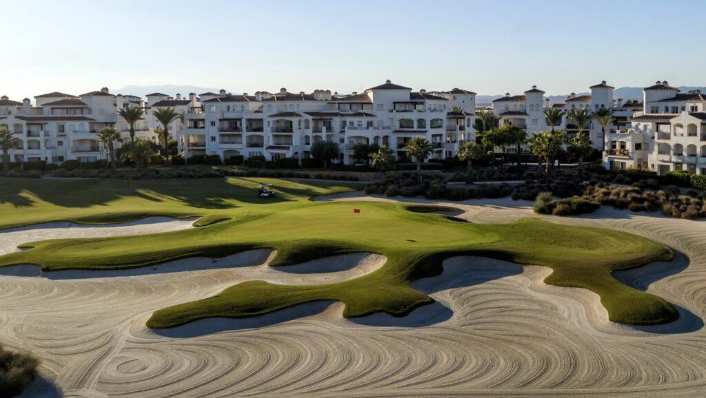 Bunkers on fairway near hole with buildings in background at La Torre Golf Course