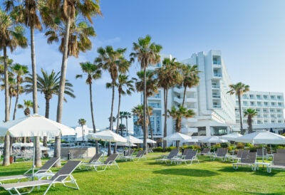 Outdoor loungers at Leonardo Plaza Cypria Maris with palm trees around