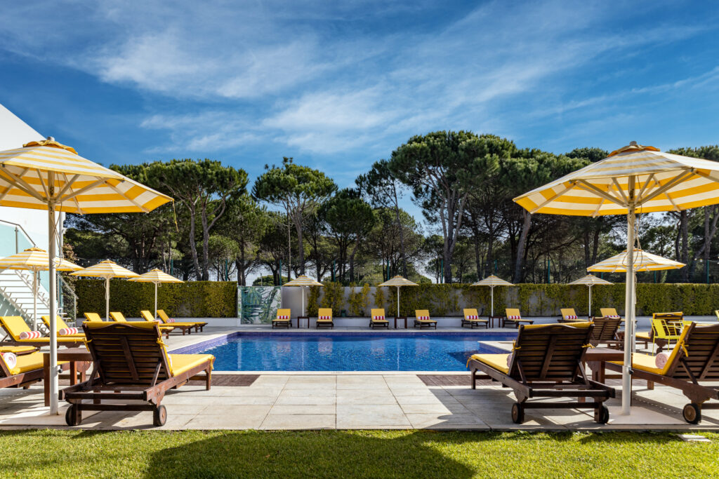 Outdoor pool with yellow sun loungers at Magnolia Hotel