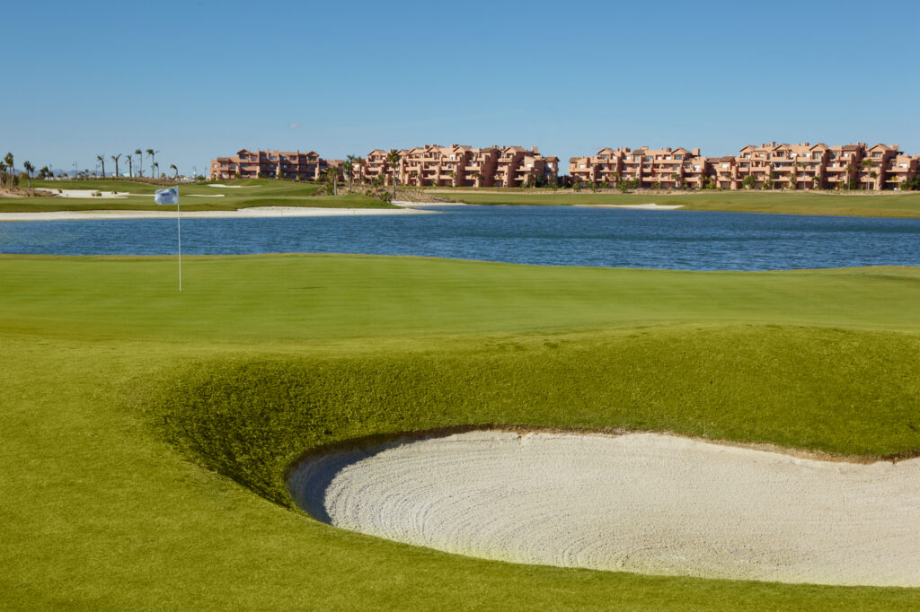 Hole with bunker and lake in background with buildings at Mar Menor Golf Course