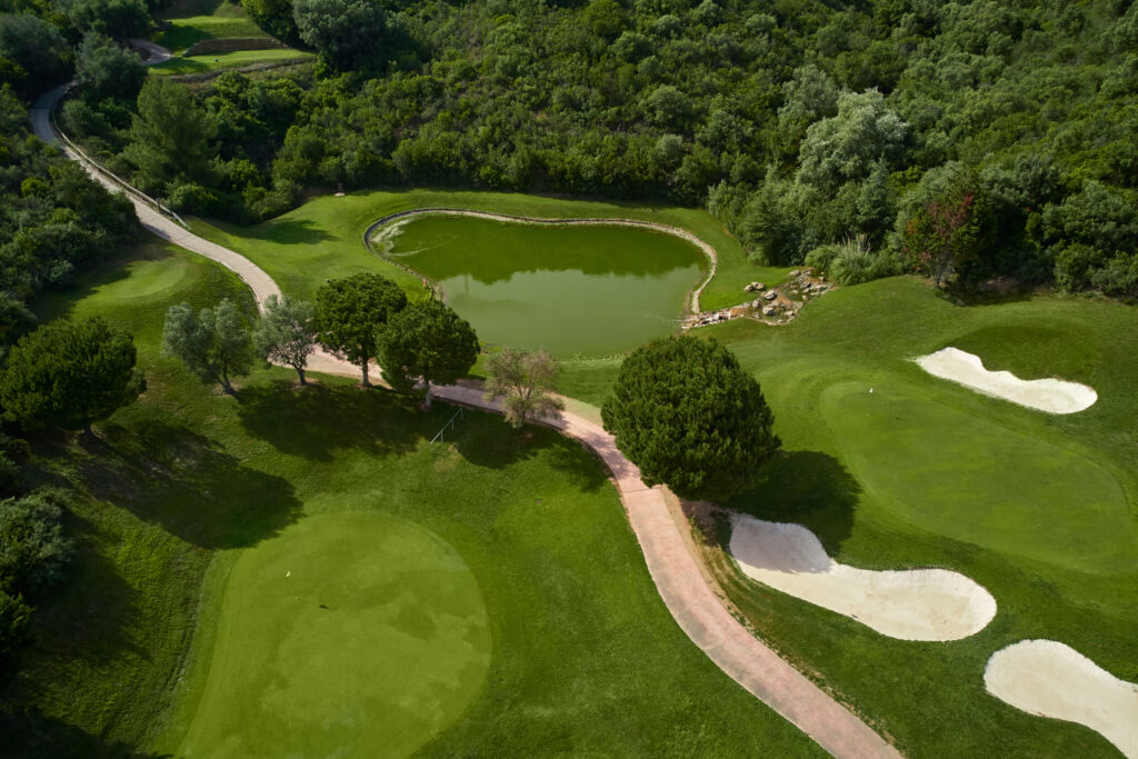 Aerial view of a lake near a hole with bunkers at Marbella Golf & Country Club with trees around