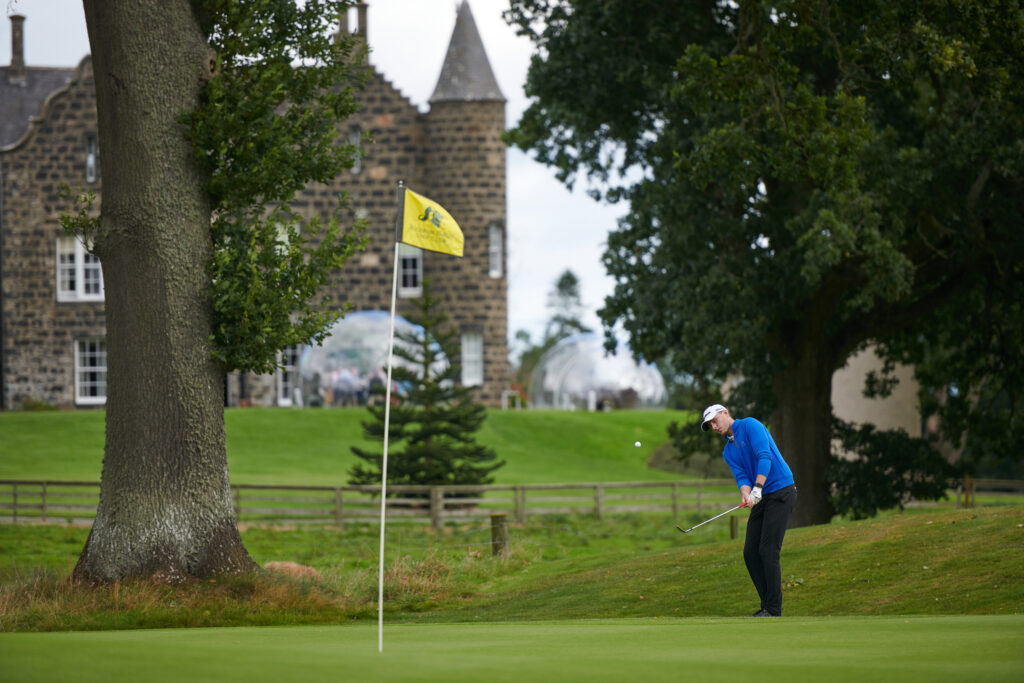 Person playing golf at Meldrum House Golf Club with building in background