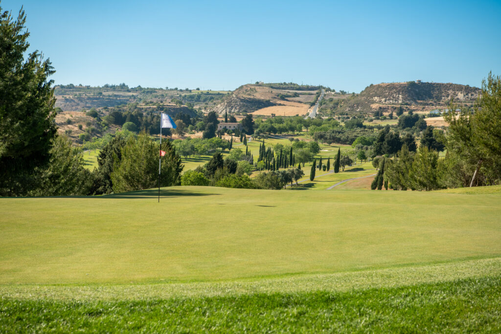 Hole with trees and hills in background at Minthis Golf Club