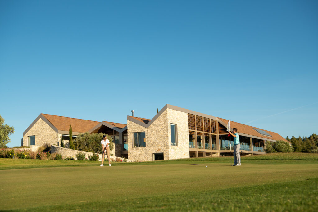 People playing golf at Minthis Golf Club with building in background