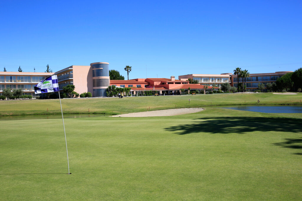 Hole with blue and white flag with buildings in background at Montado Golf Course