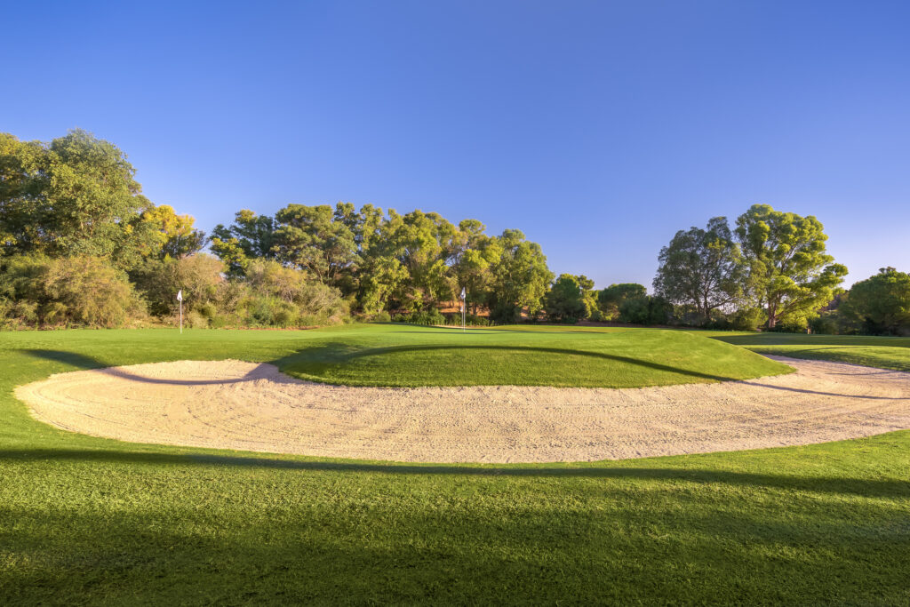 Hole with bunker around with trees in the background at Montecastillo Golf Course