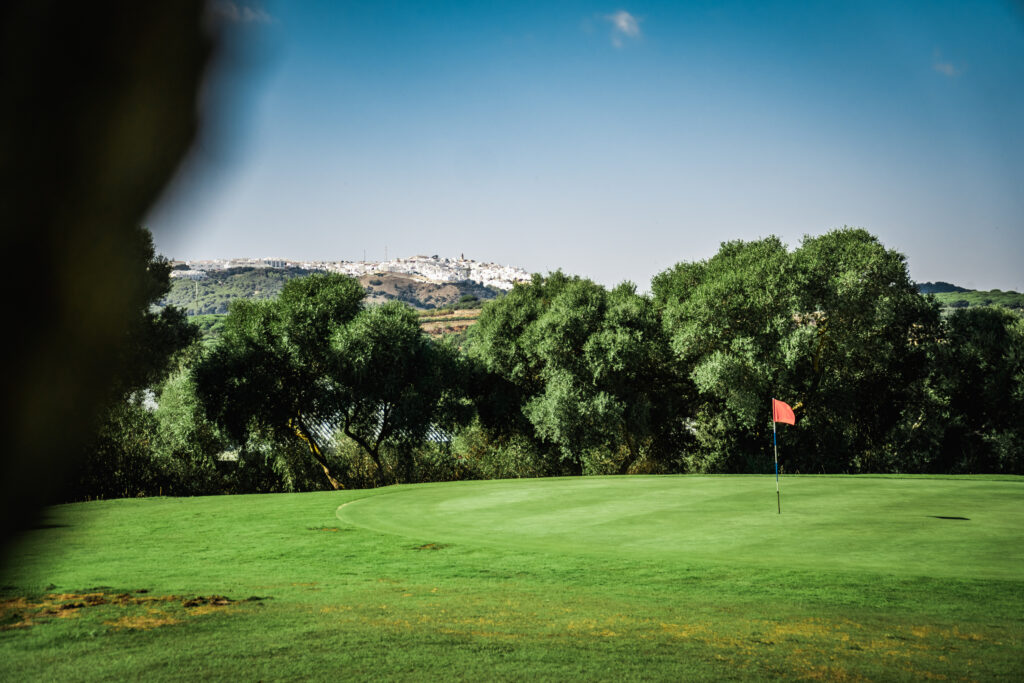 Hole with red flag and trees in background at Montenmedio Golf & Country Club