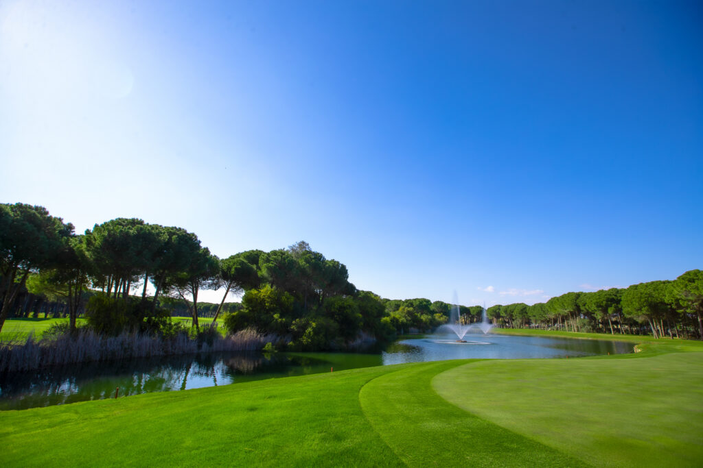 Fairway with lake and fountains with trees around at Montgomerie Maxx Royal Golf Course