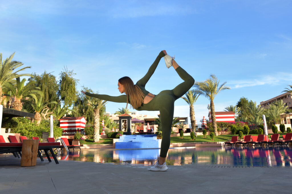 Person doing outdoor yoga by the pool at Movenpick Hotel Mansour Eddahbi Marrakech