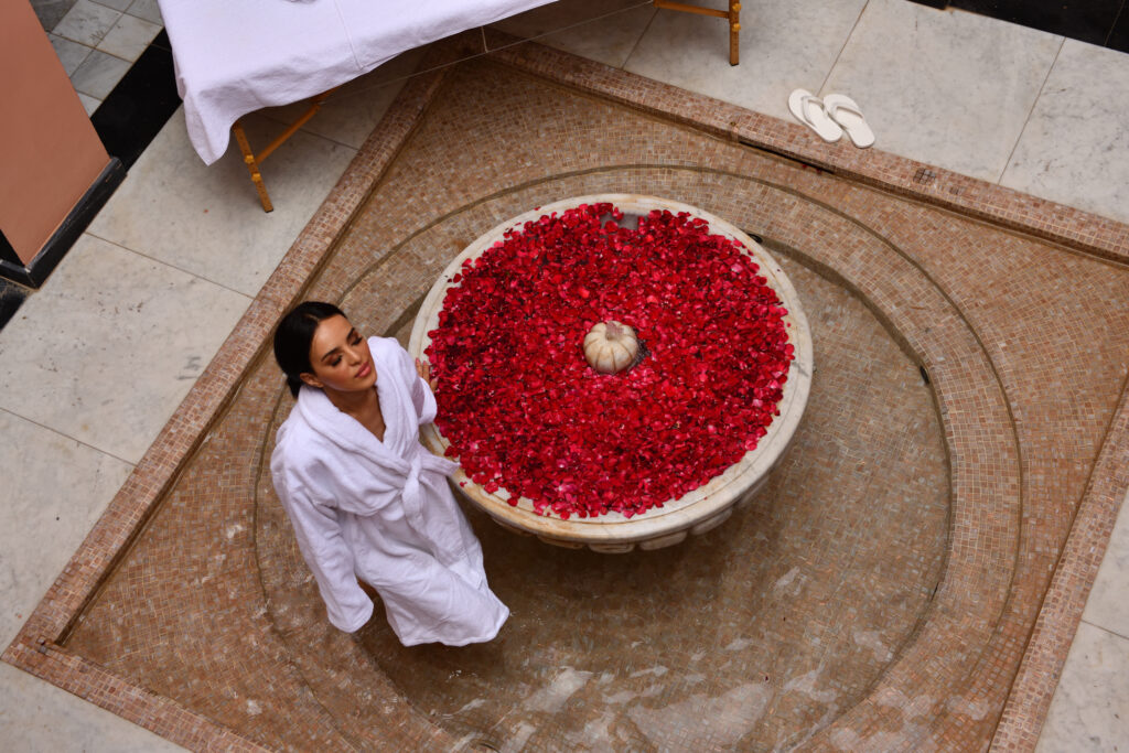 Person relaxing by water bath filled with flowers at Movenpick Hotel Mansour Eddahbi Marrakech