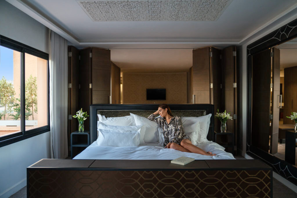 Person relaxing in their double bed accommodation at Movenpick Hotel Mansour Eddahbi Marrakech