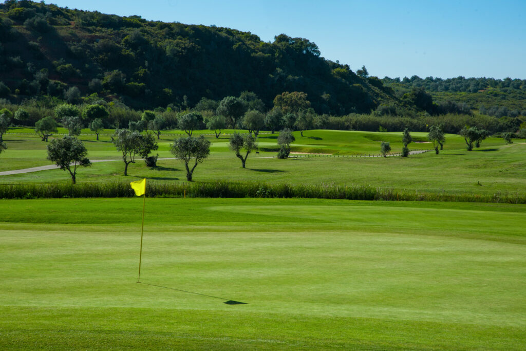 A hole at Morgado golf course with trees and hills in background