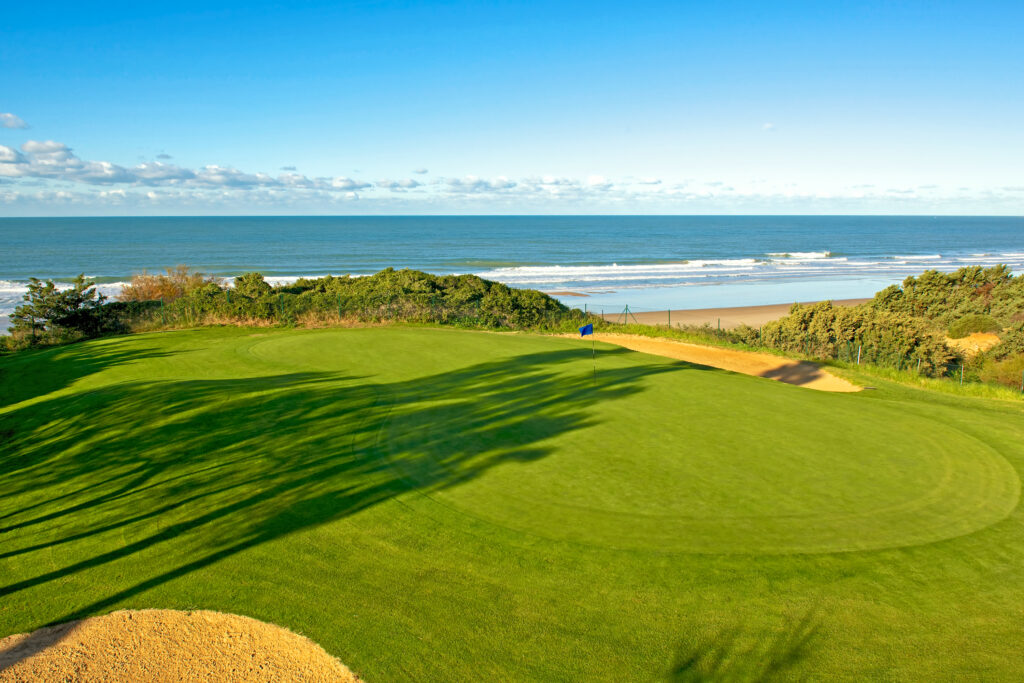 A hole with blue flag and ocean view at Real Novo Sancti Petri Golf Club - B Course