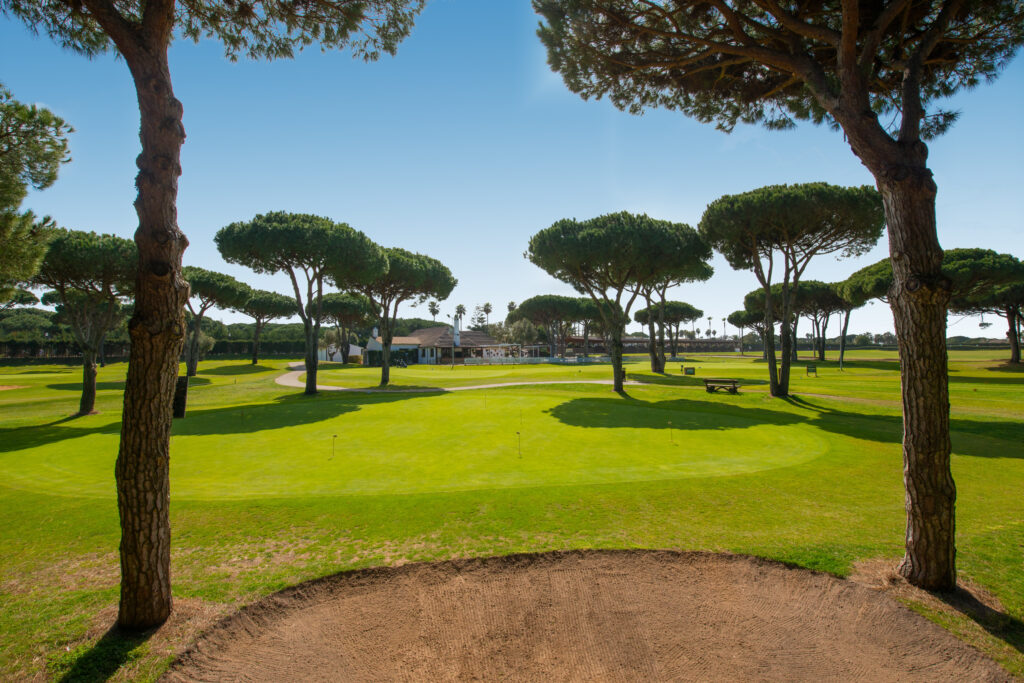 Bunker with trees and building in the background at Real Novo Sancti Petri Golf Club - B Course