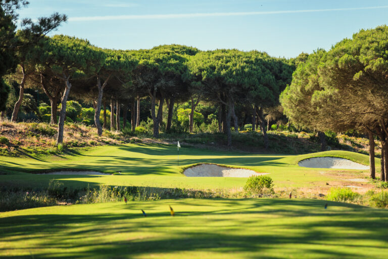 Hole with bunkers surrounded by trees at Oitavos Dunes Golf Course