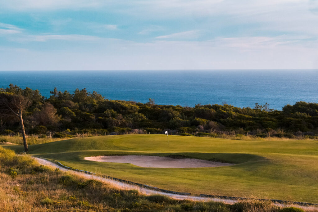 Hole with a bunker at Oitavos Dunes Golf Course with ocean view in background