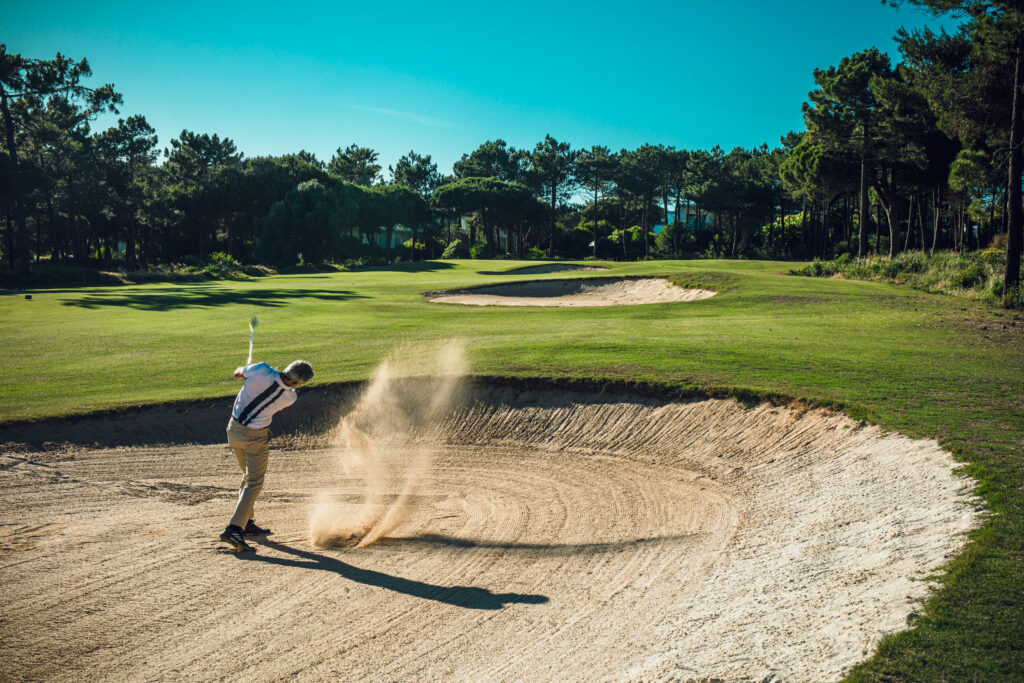 Man playing golf out of a bunker at Oitavos Dunes Golf Course