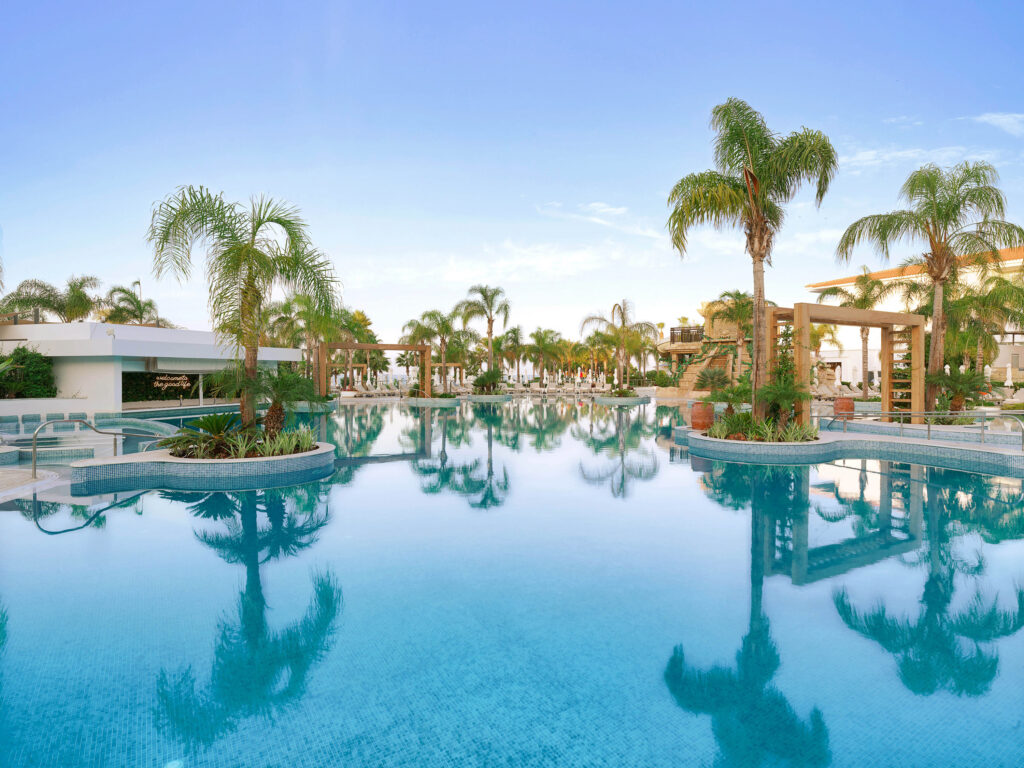 Outdoor pool with palm trees around at Olympic Lagoon Hotel