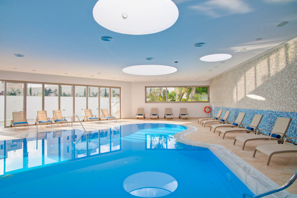 Indoor pool with loungers around at Olympic Lagoon Hotel