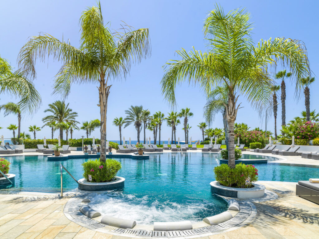 Outdoor pool at Olympic Lagoon Hotel with sun loungers and palm trees