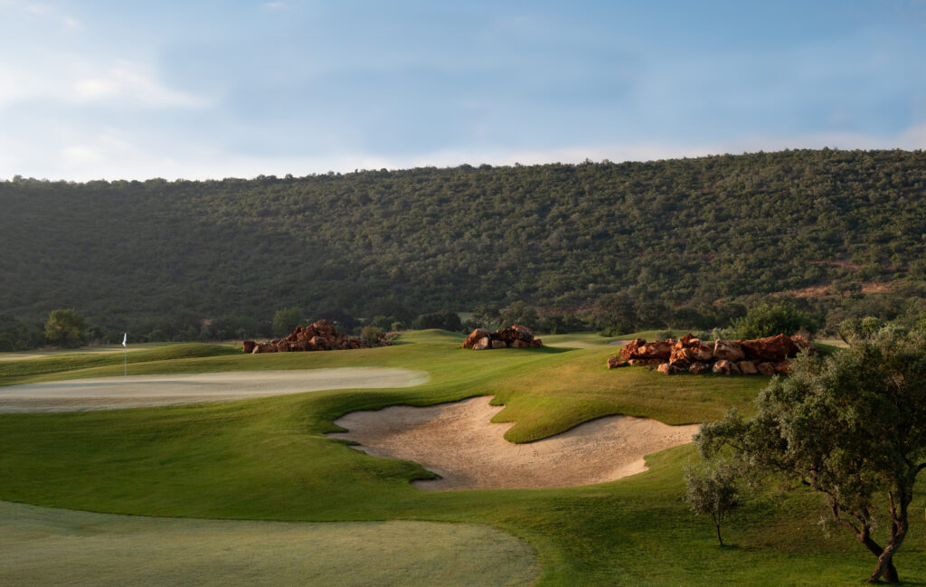 A green with bunker surrounded by hillside at Ombria Golf Course