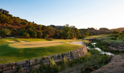 A green with water hazard and hills surrounding at Ombria Golf Course