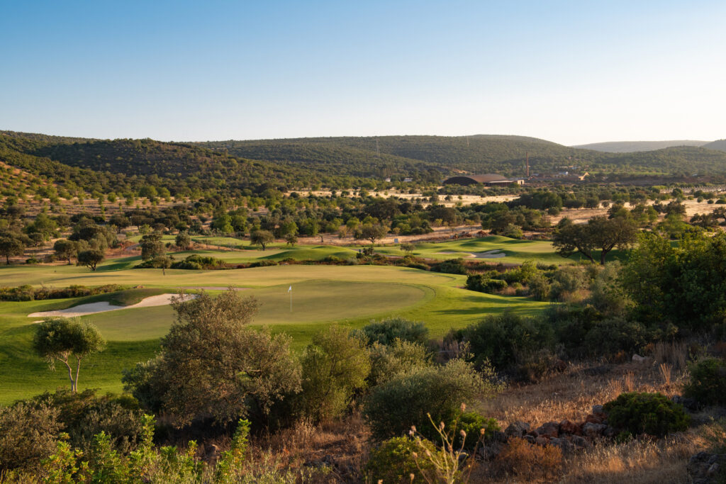 A green surrounded by trees and hillsides at Ombria Golf Course