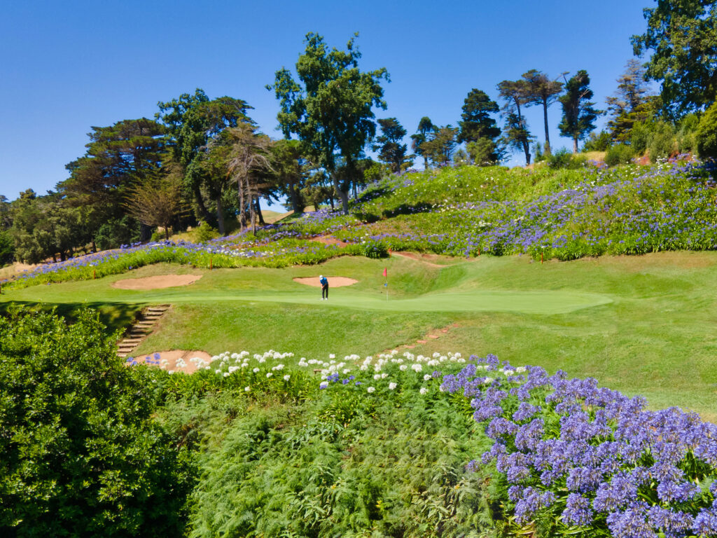 Person playing golf at Palheiro Golf Course with flowers all around