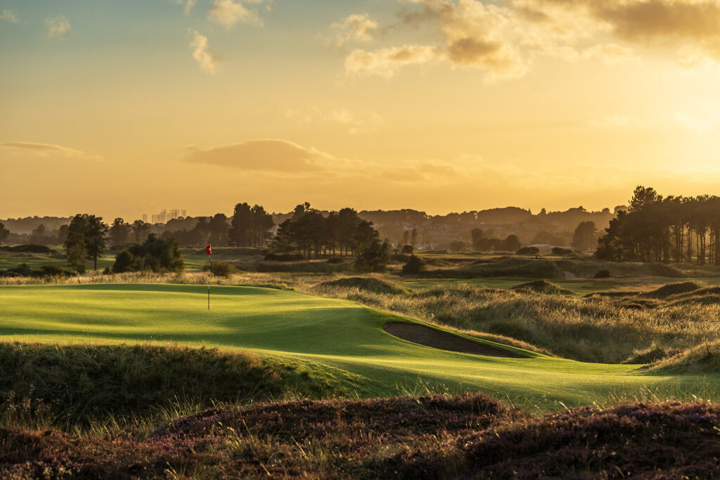 Hole with red flag at Panmure Golf Club with trees in background