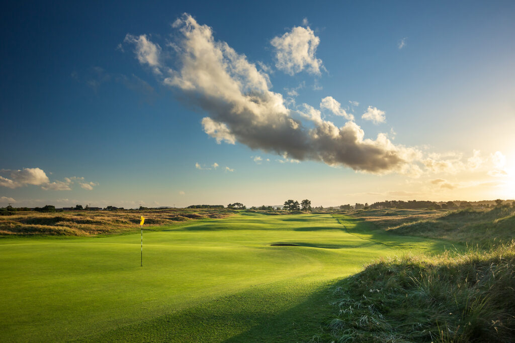 Hole with yellow flag at Panmure Golf Club with fairway behind it