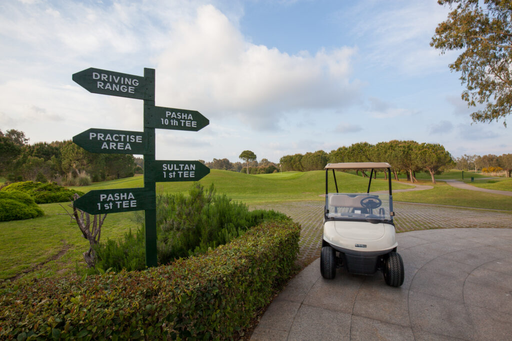 Direction signs with buggy with fairway in background at The Pasha Golf Course