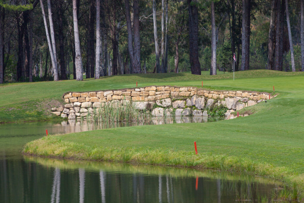 Lake with stone wall and trees in background at The Pasha Golf Course